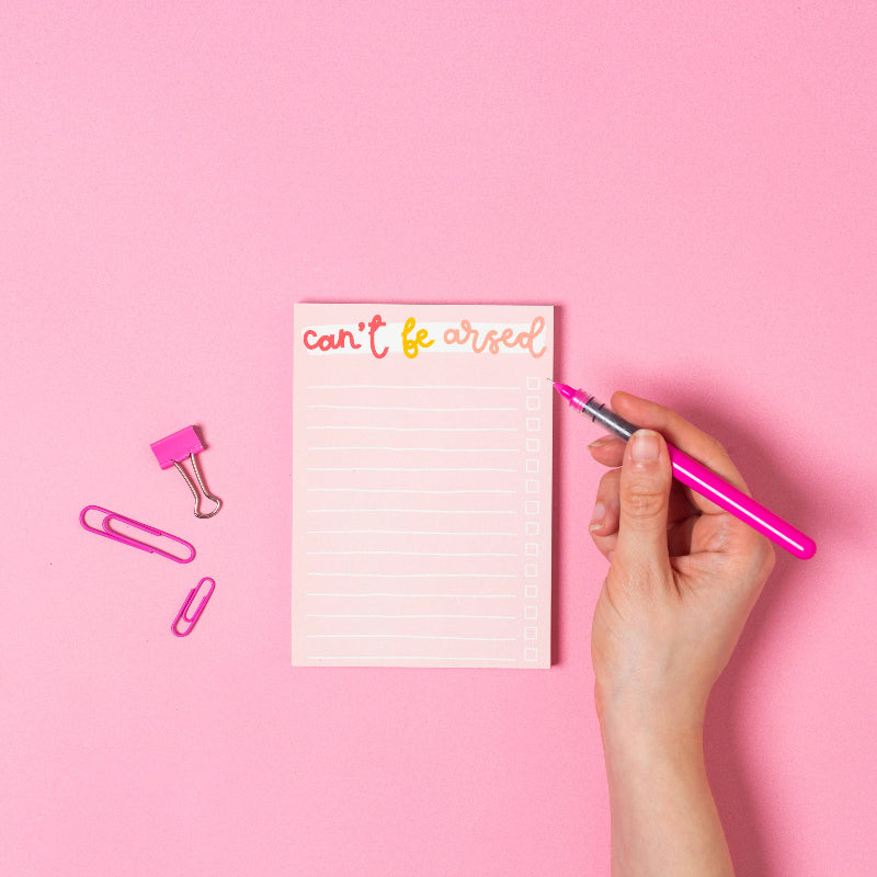 Hand holding a pink pen above a notepad with 'can't be aired' text on a pink background