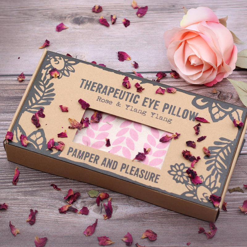 Therapeutic eye pillow packaging with rose petals on a wooden surface