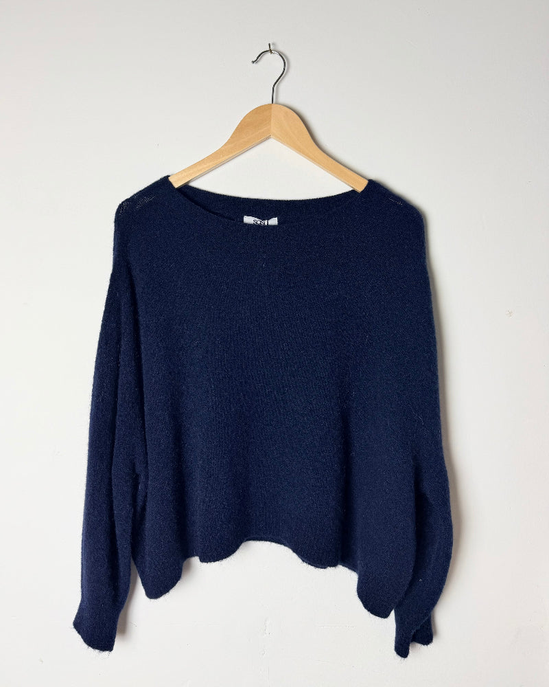 Navy Alpaca Slouch Sweater Dark Blue on a wooden hanger against a white background