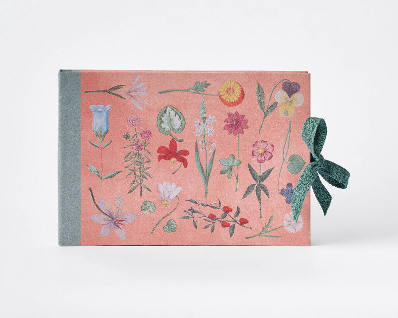 Book with floral design and green ribbon on a white background