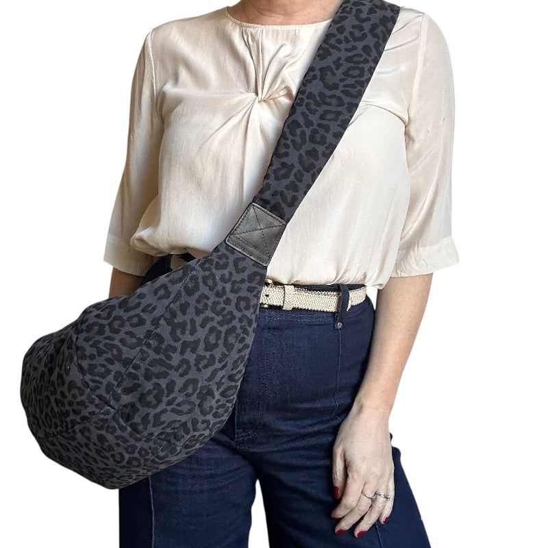 Person wearing a white blouse, blue jeans, and a gray leopard print bag on a white background