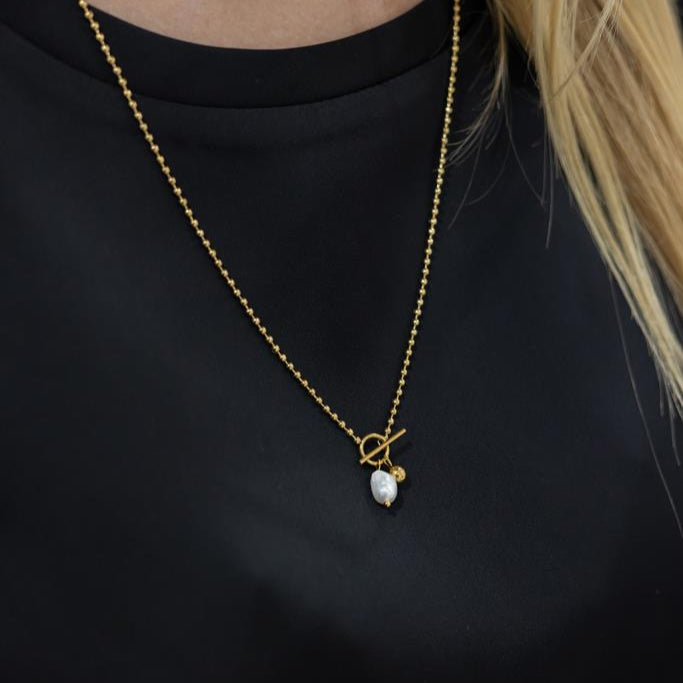 Gold necklace with a pendant on a black background