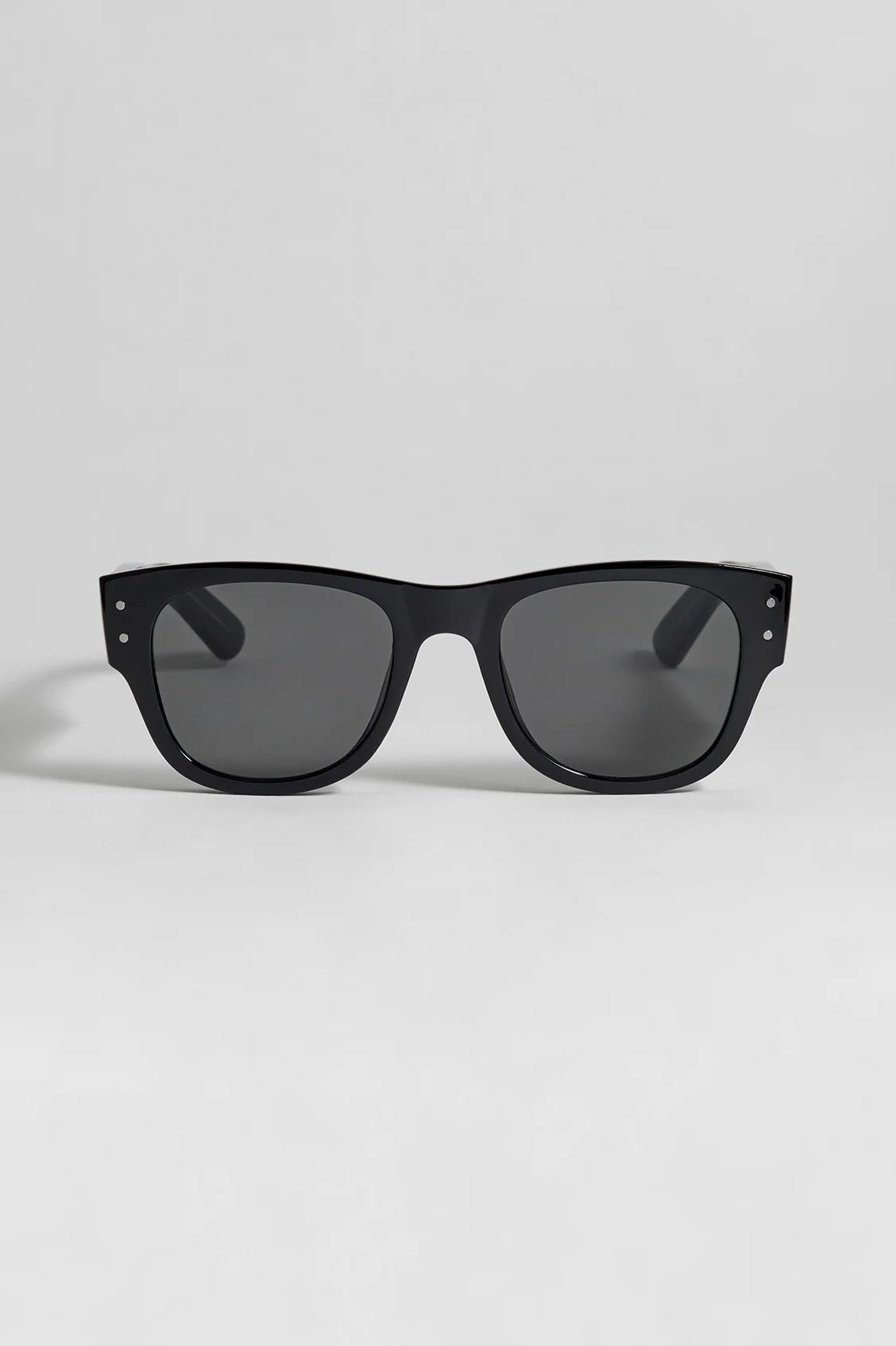 Black sunglasses with dark lenses on a light gray background