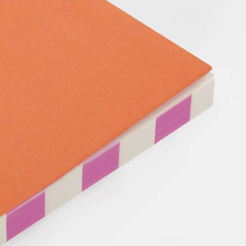 Rectangular object with orange top and purple and white striped sides on a light gray background