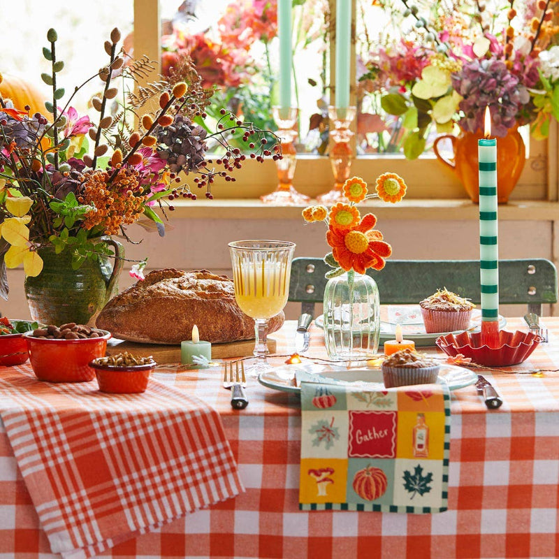 Decorated table with flowers, bread, and colorful tableware in a bright room.