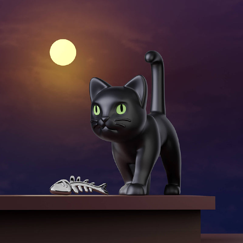 A glossy black cat figurine with bright green eyes stands on a brown platform against a purple night sky with a glowing yellow moon. A small silver fish skeleton lies beside the cat.