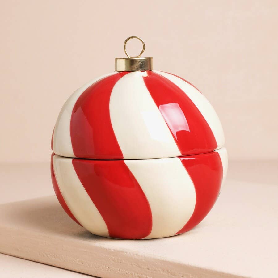 Red and white striped container with a gold lid on a beige background