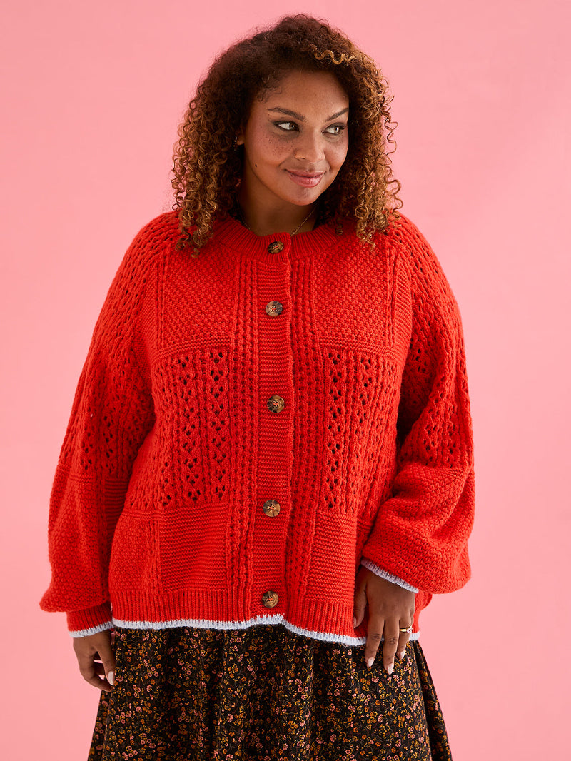 Woman wearing Cara &amp; The Sky Brigit Pointelle Cardigan a red knitted cardigan on a pink background