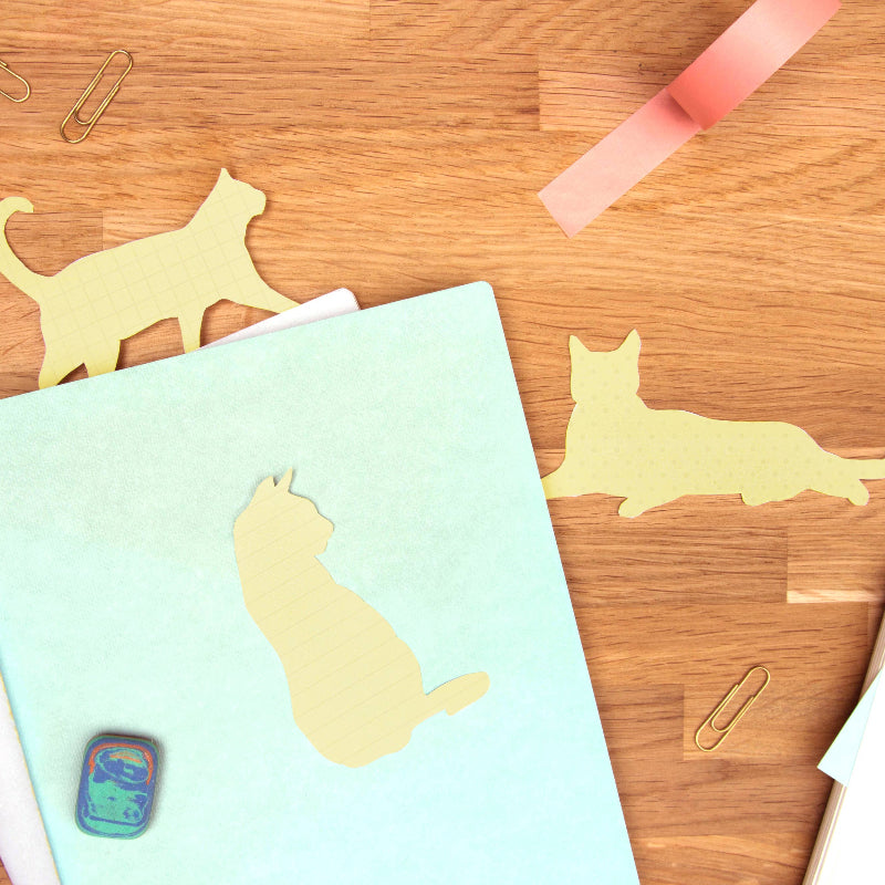 Notebook with cat-shaped cutouts on a wooden surface