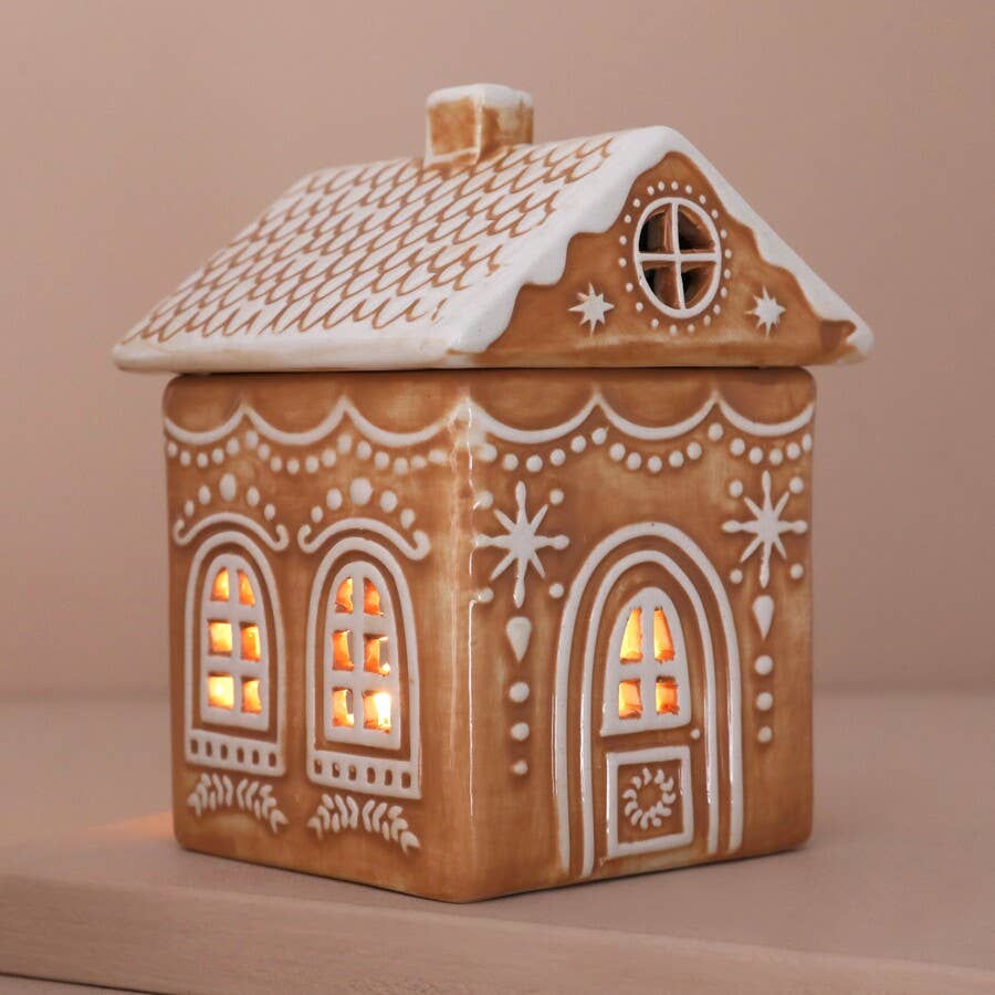 Ceramic ginger bread house-shaped lantern with decorative details on a beige background