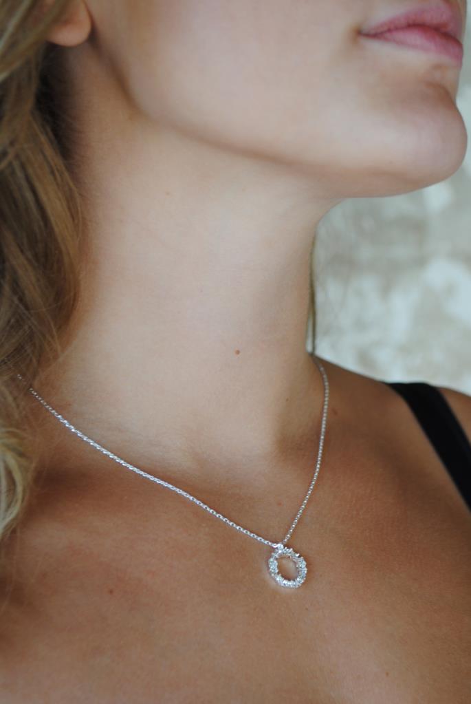 Close-up of a necklace with a circular pendant on a person's neck.