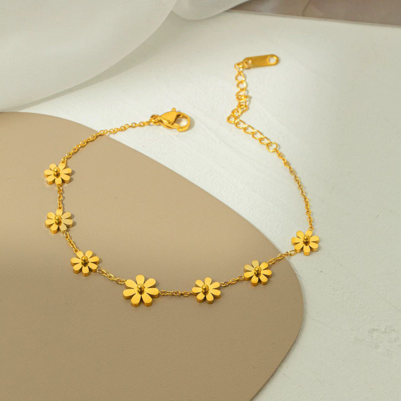 Gold bracelet with floral designs on a neutral background