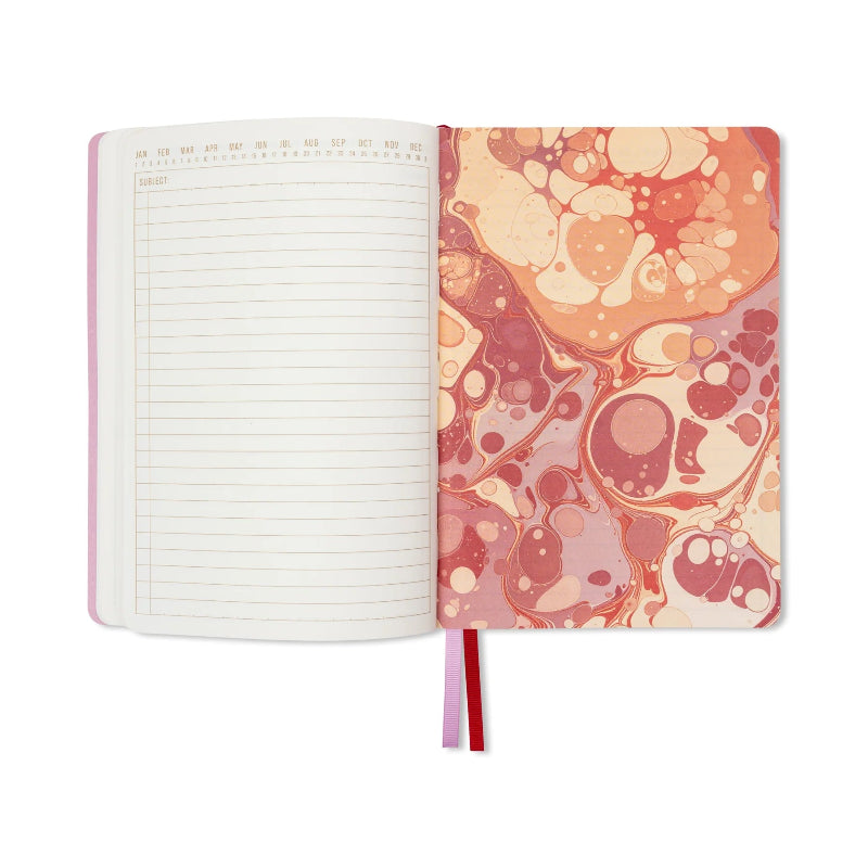 An open notebook with lined pages on the left and a pink, orange, and cream marbled cover on the right, shown on a plain white background.