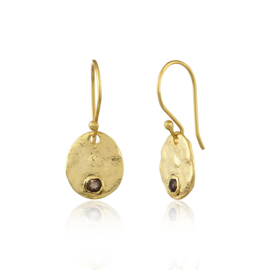 Gold earrings with round designs and dark gemstones on a white background