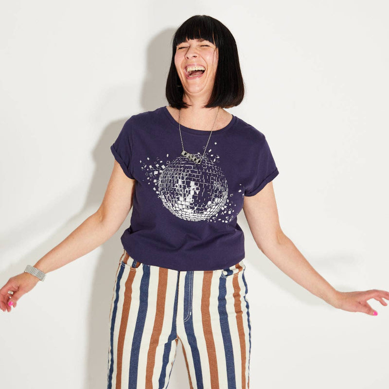 Person wearing a purple t-shirt with a disco ball design and striped pants on a white background