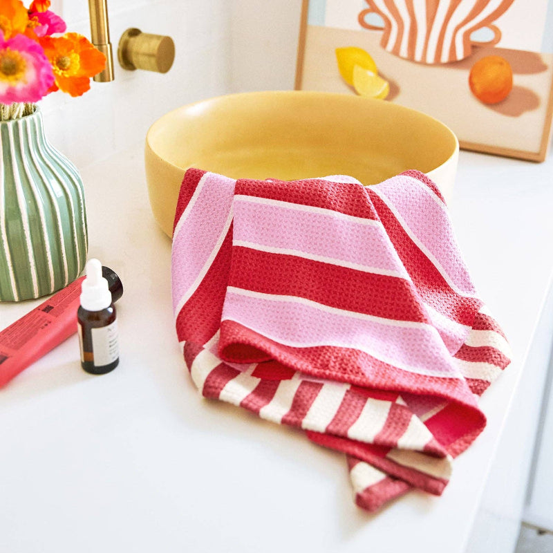 Red and white striped towel on a bathroom counter with a yellow sink and decorative items.