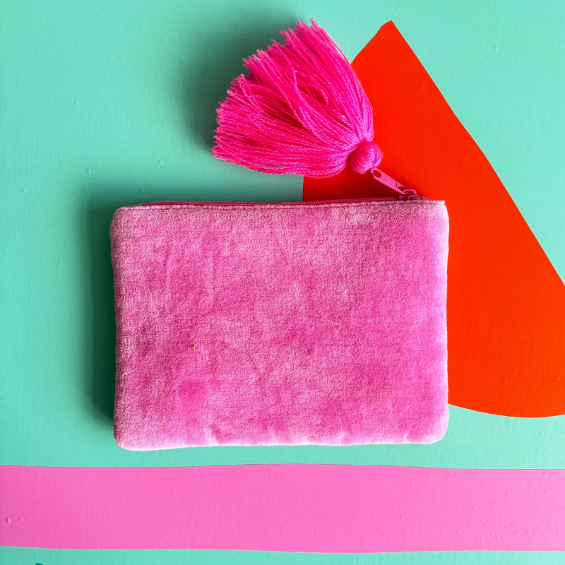 Pink clutch bag with a tassel on a colorful geometric background