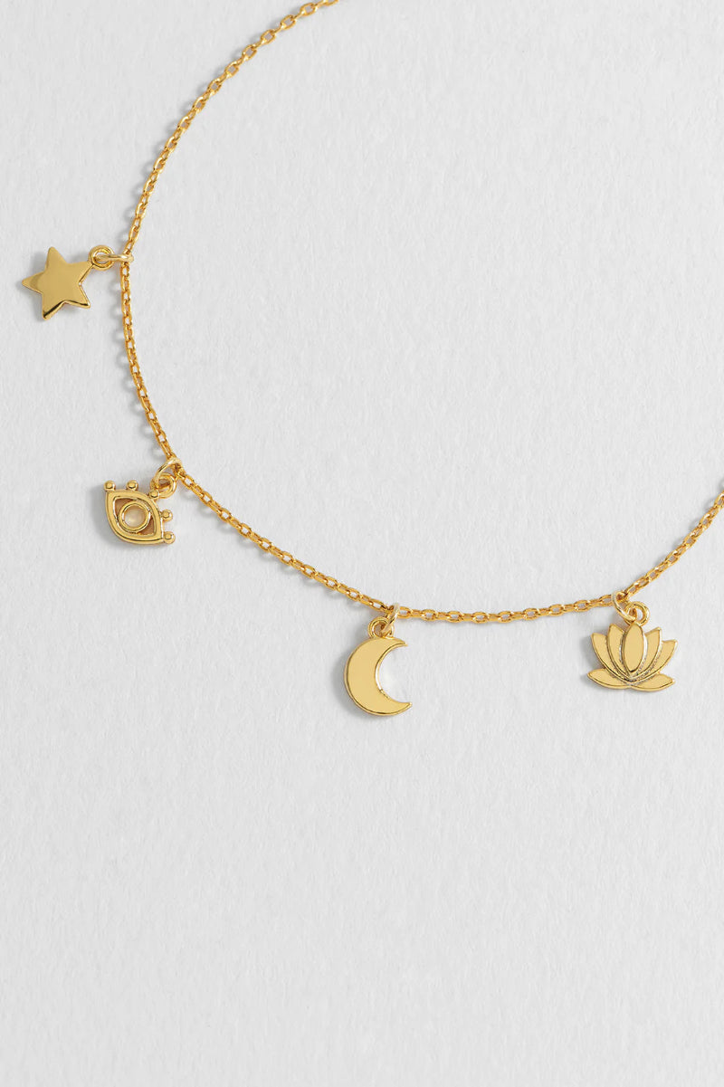 Gold bracelet with various charms on a light gray background