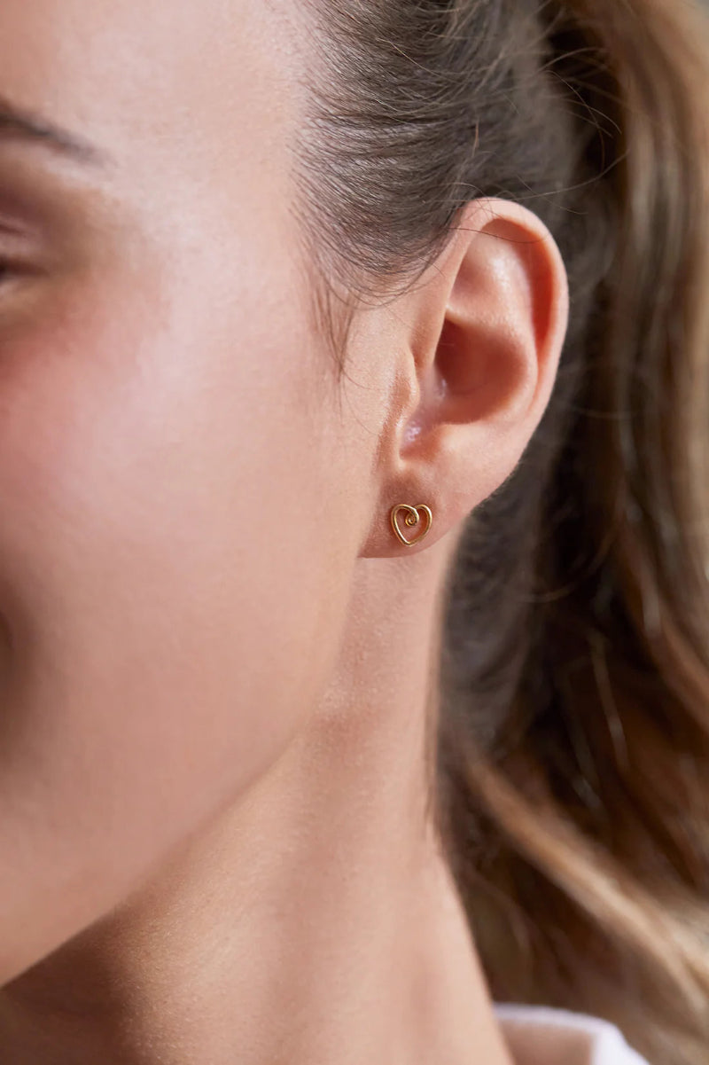 Close-up of a person wearing a gold heart-shaped earring.