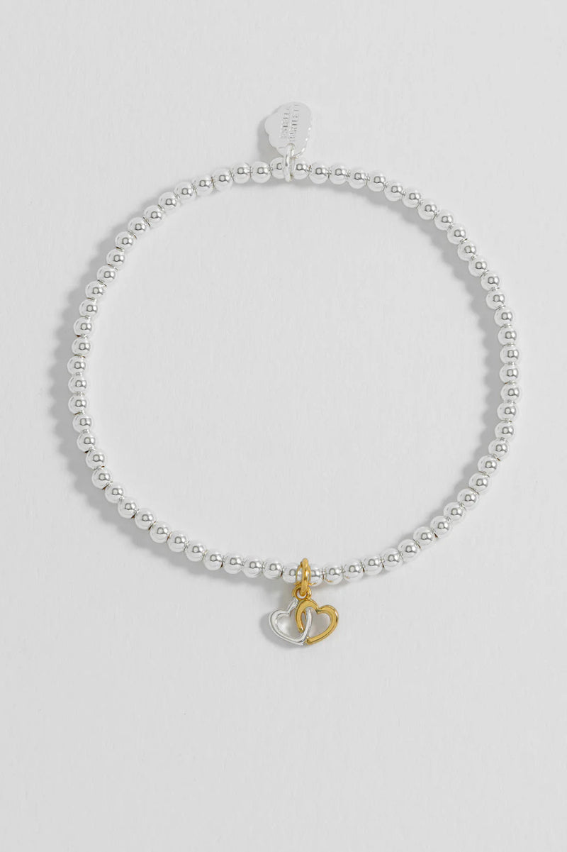 Silver bracelet with a small gold charm on a light gray background