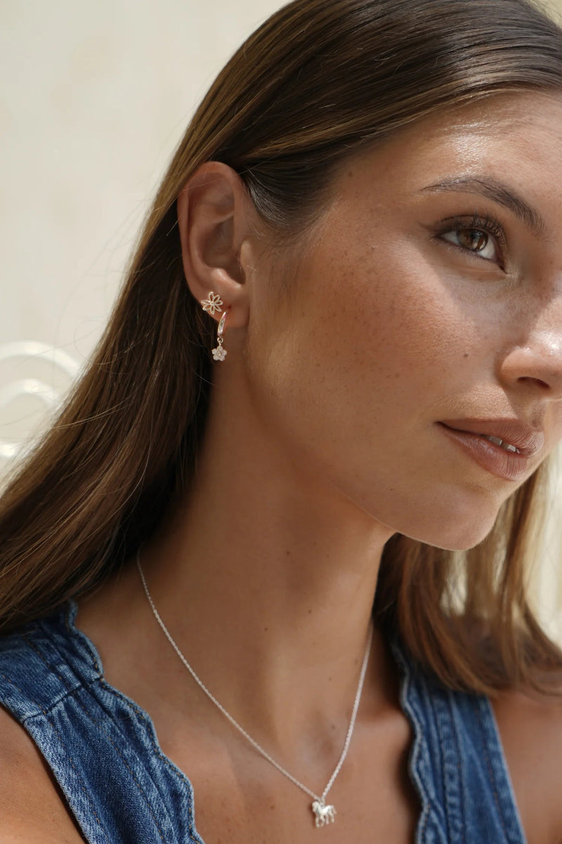 Woman wearing a silver necklace and earrings with a neutral background
