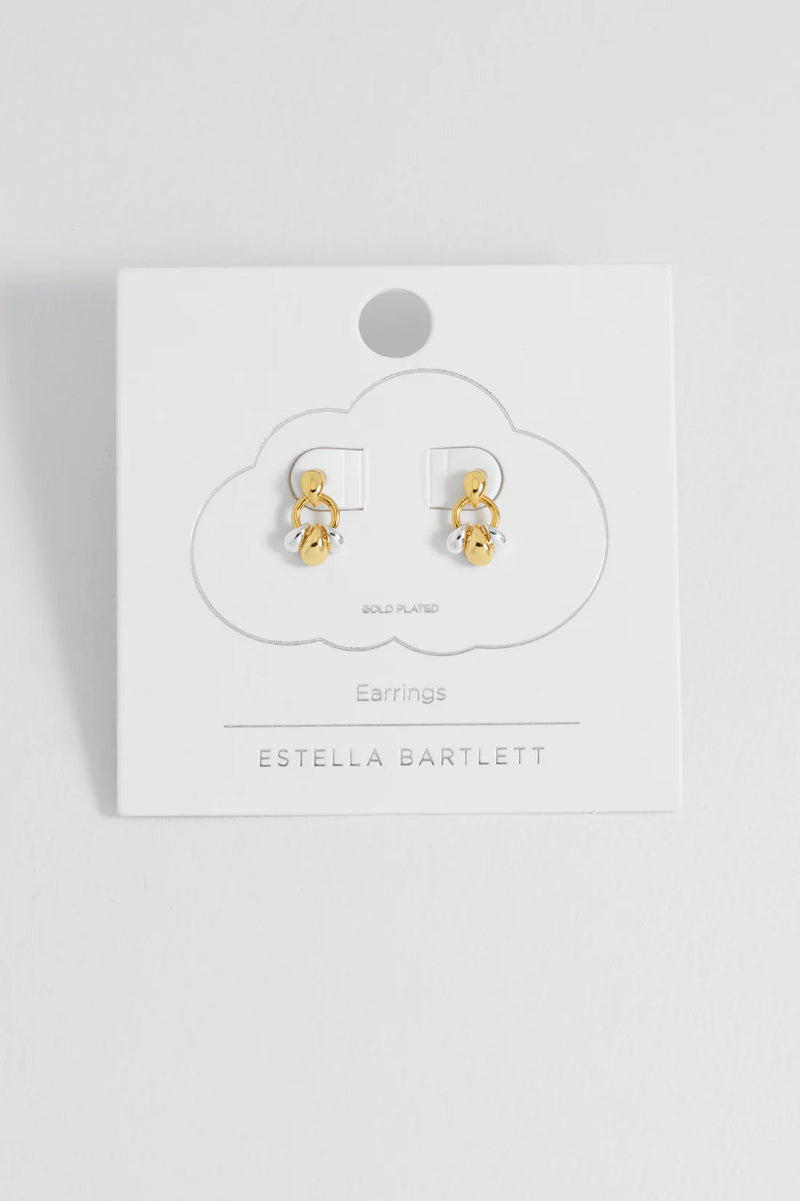 Gold earrings on a white card with 'Estella Bartlett' branding against a white background