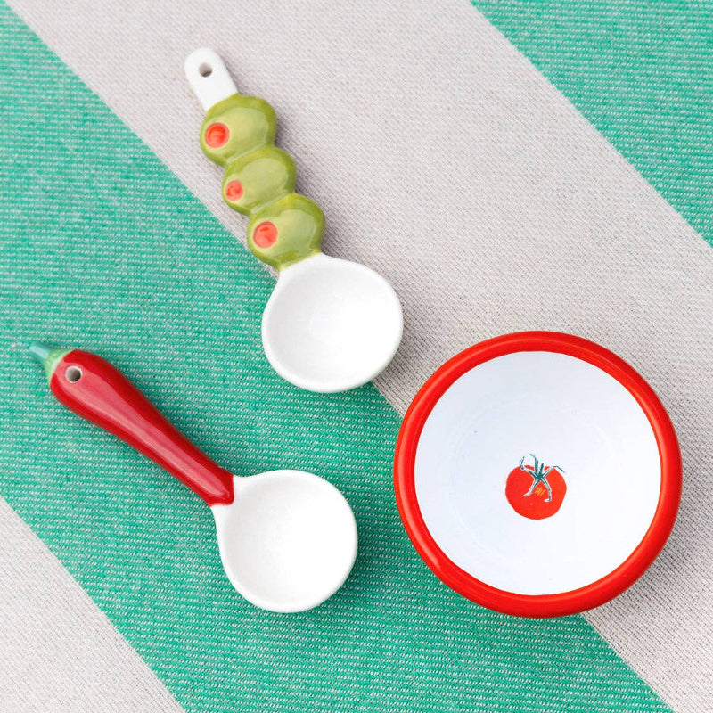 Set of ceramic spoons with red and green accents on a textured surface