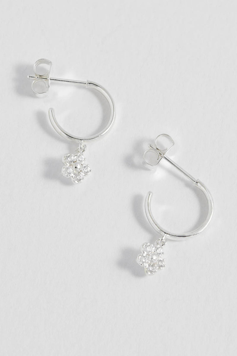 Silver hoop earrings with small round embellishments on a light gray background