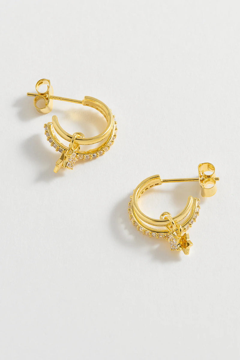 Gold hoop earrings with small stones on a light gray background