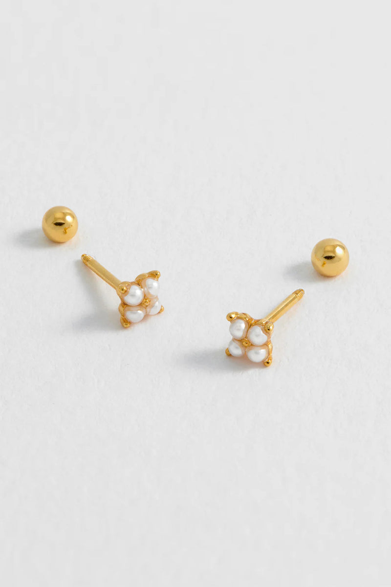 Gold and pearl stud earrings on a light gray background