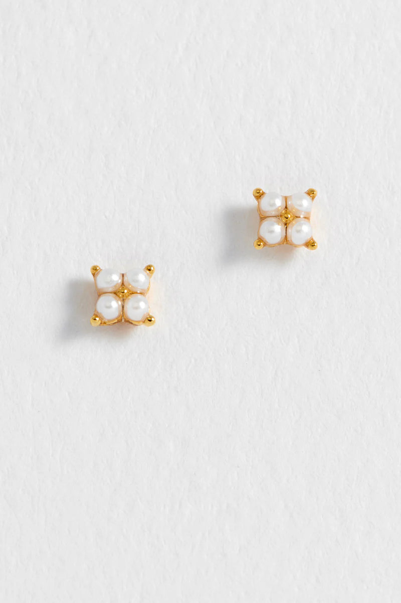 Pair of gold earrings with pearl-like stones on a light gray background
