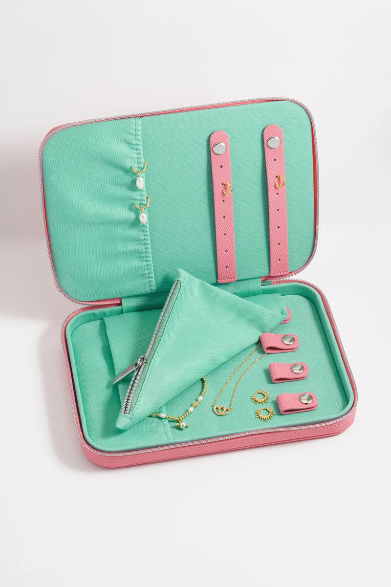 Open turquoise jewelry case with pink accents containing jewelry on a white background