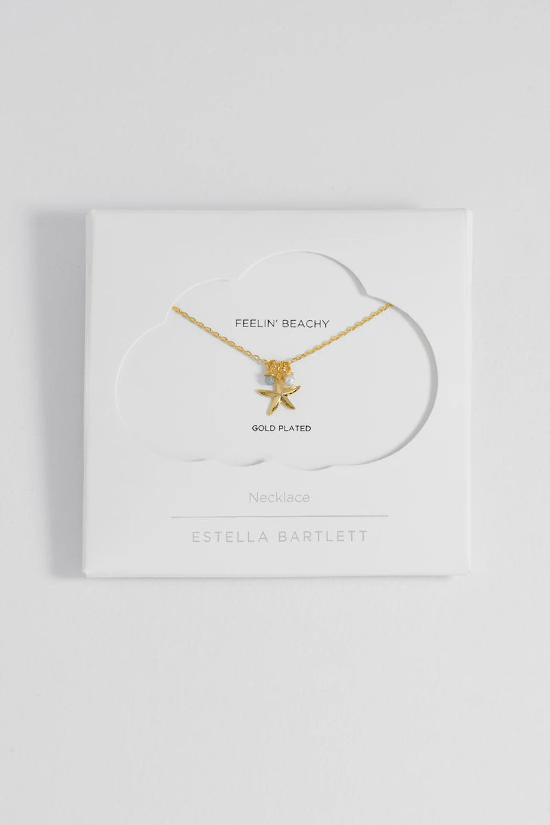 Gold-plated necklace with starfish charm on a white card with brand name.