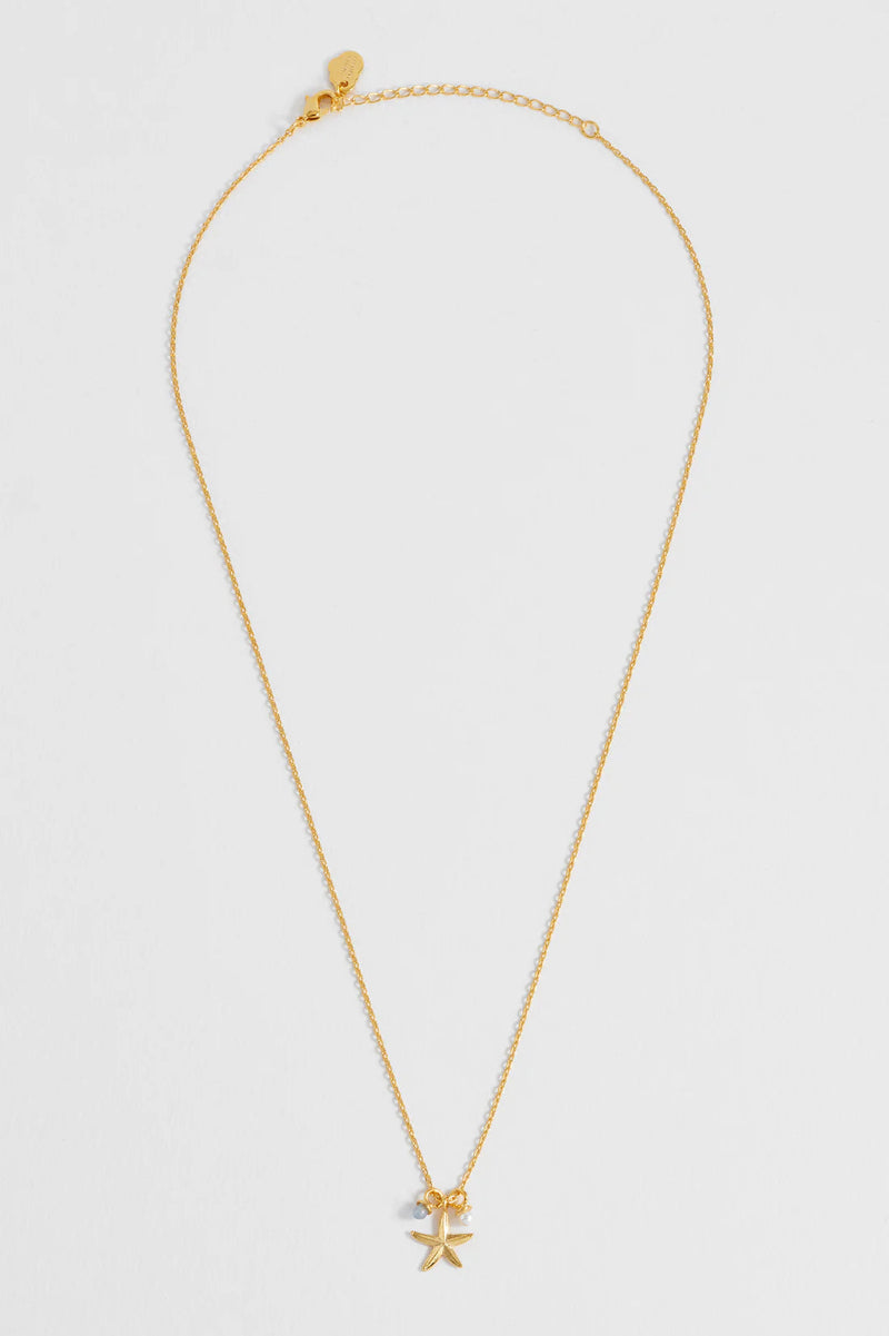 Gold necklace with a small pendant on a light gray background