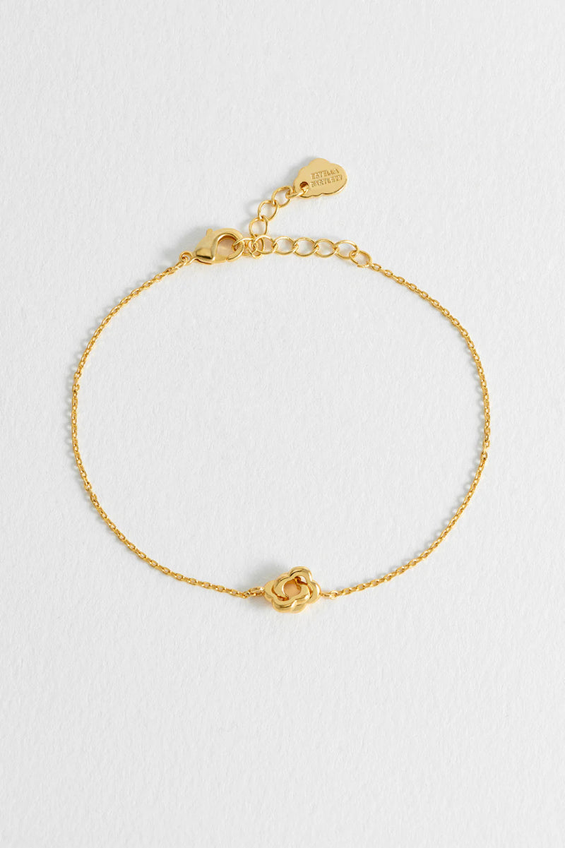 Gold bracelet with a rose charm on a light gray background