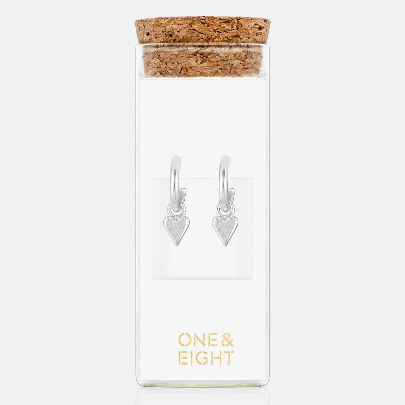 Heart-shaped earrings in a clear glass jar with cork lid on a white background, branded 'ONE & EIGHT'.