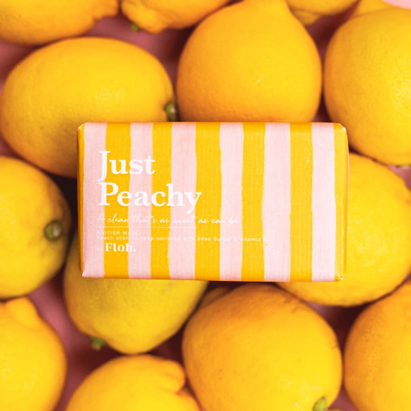 Bar of soap with 'Just Peachy' packaging surrounded by lemons