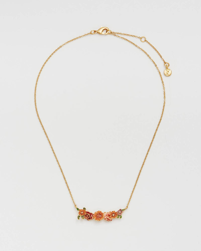 A delicate gold chain necklace featuring a small horizontal bar with three peach and orange flowers and green leaves, displayed on a clean white background.