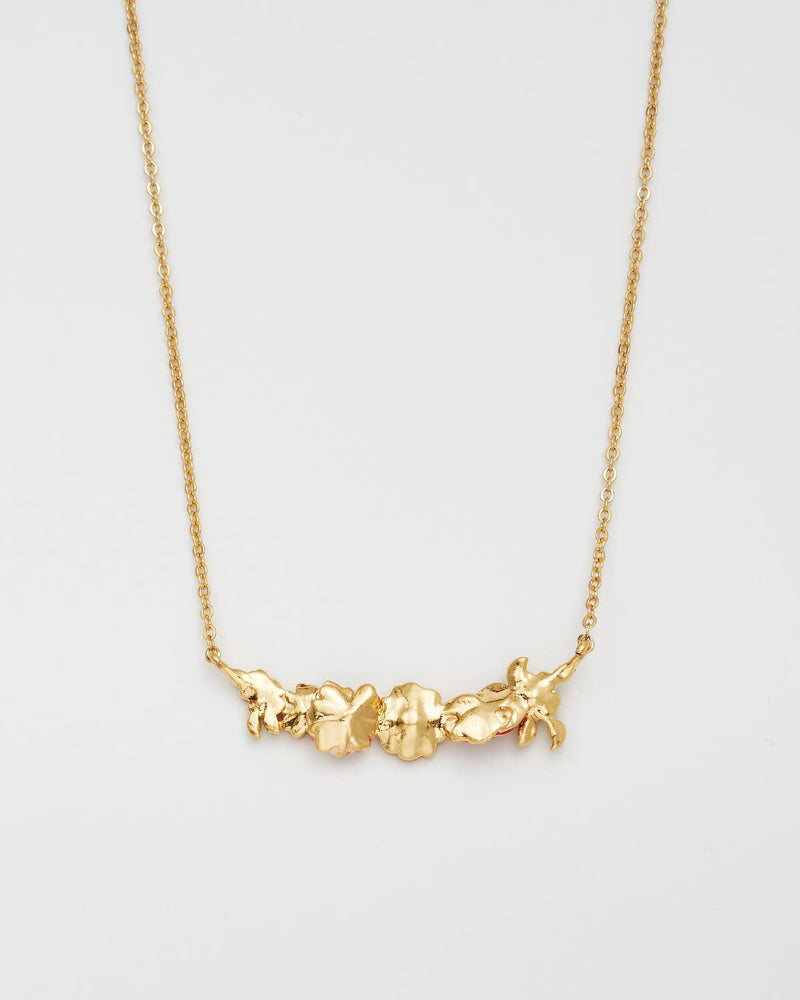 A gold necklace featuring three textured, organic-shaped beads or charms connected by a delicate gold chain, shown against a plain light gray background.