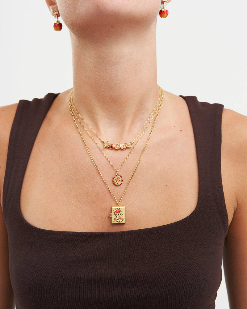Close-up of a person wearing gold necklaces with pendants on a plain background