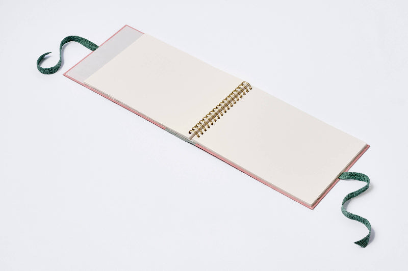 Open notebook with a pink cover and green ribbon on a white background
