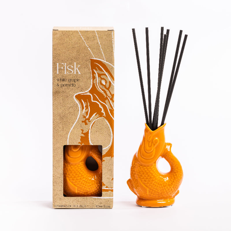 Orange fish-shaped diffuser with black sticks and packaging on a white background