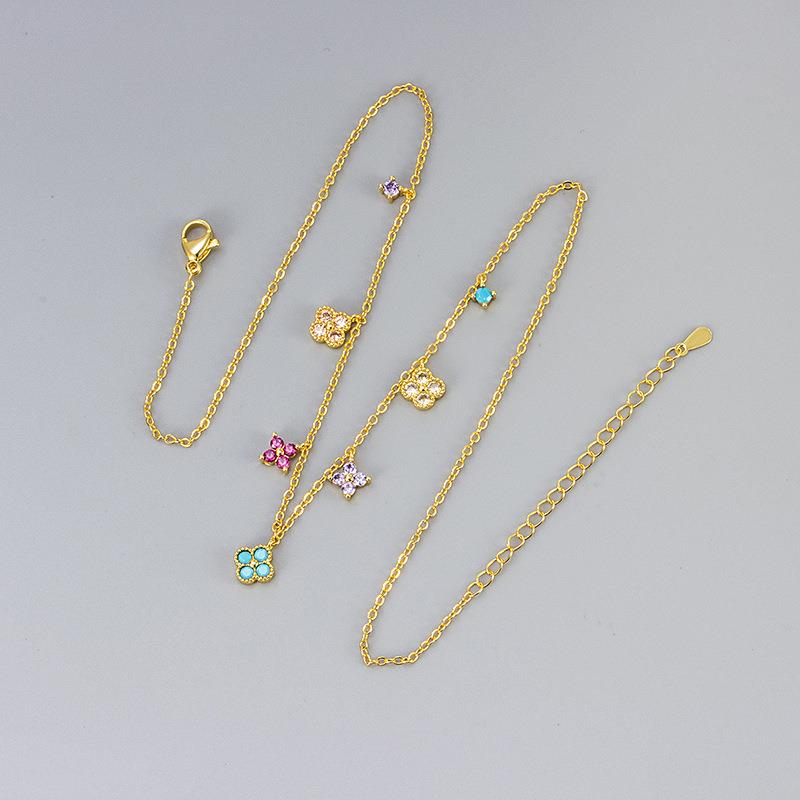 Gold chain necklace with floral pendants on a gray background