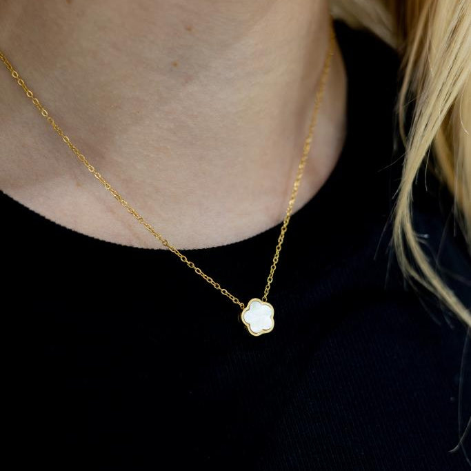 Gold necklace with a pendant on a person wearing a black top.