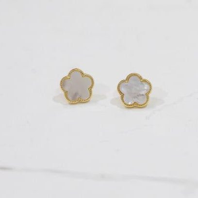 Pair of gold and white flower-shaped earrings on a light gray background