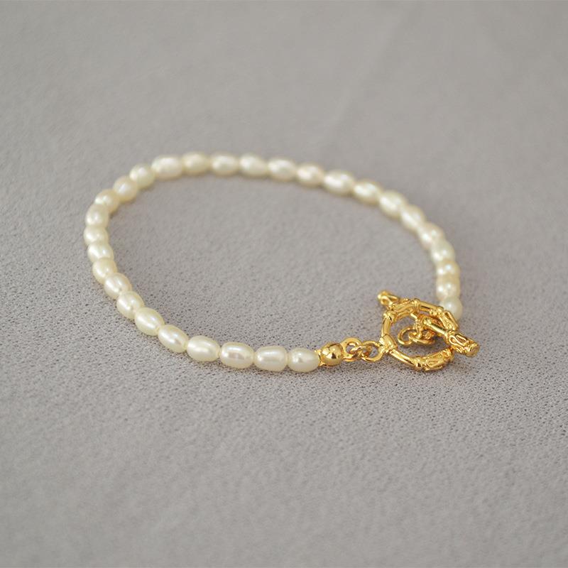 Pearl bracelet with a gold clasp on a gray background