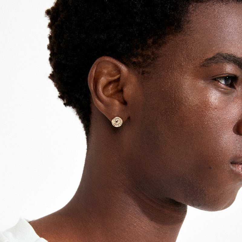 Close-up of a person wearing gold earrings on a white background