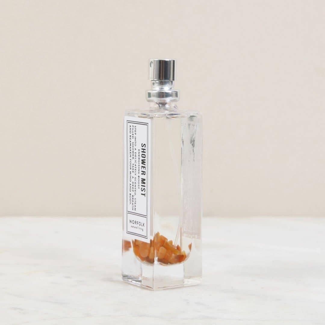 Clear spray bottle with a label on a light beige background