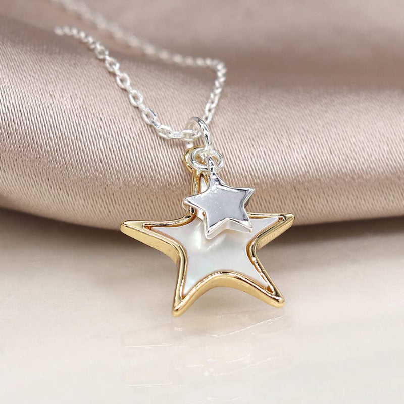 Star-shaped pendant necklace with gold and silver finish on a beige fabric background