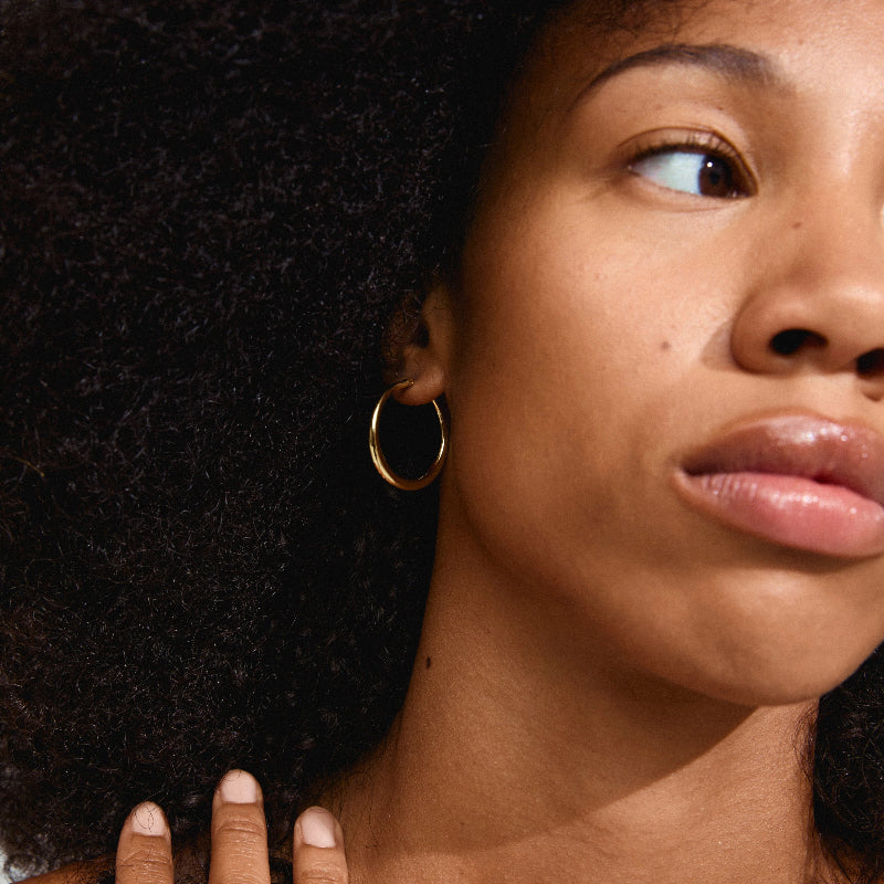 Close-up of a woman with an afro and gold hoop earrings.